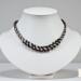 Black white and grey satin Kumihimo necklace displayed on white jewelry bust, highlighting spiral braid and beaded focal section
